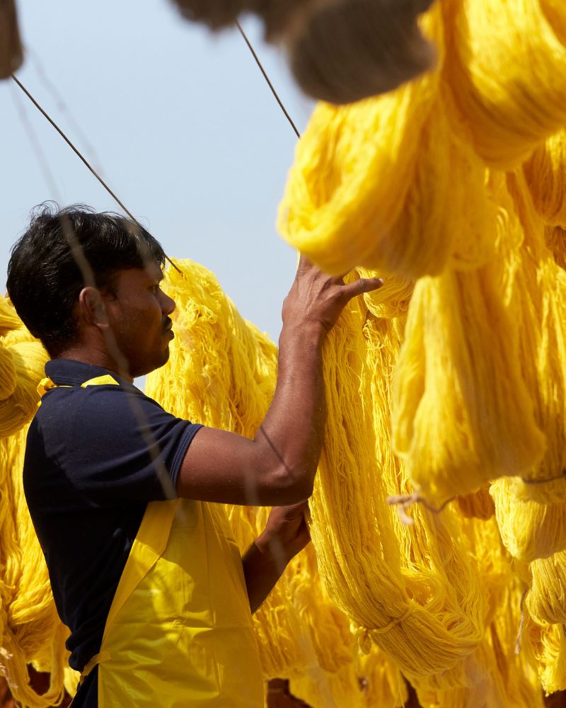 Una persona trabajando con lana teñida de amarillo