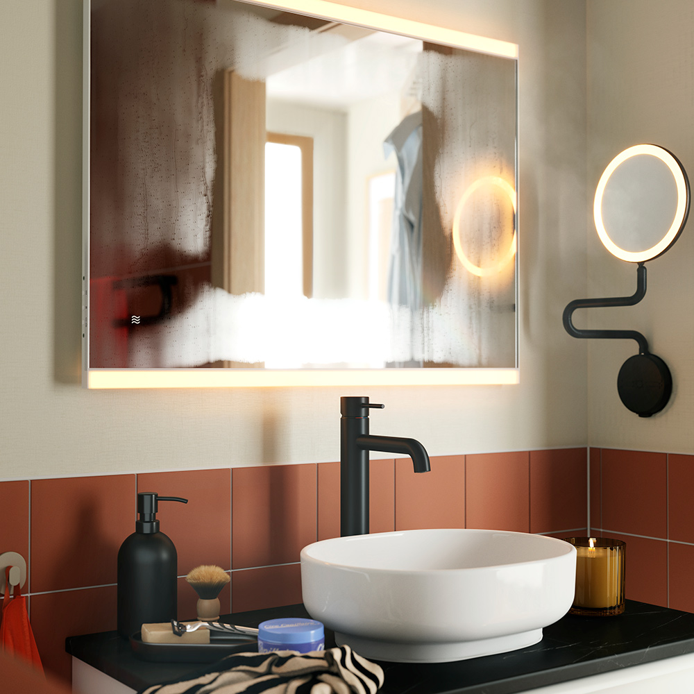 A KÄRRSJÖN mirror with integrated lighting mounted above a round washbasin and black tap, in a terracottatiled bathroom.