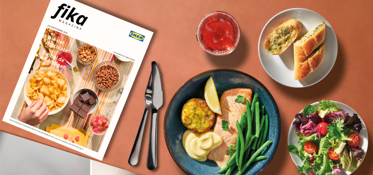 Top-down view of a table featuring IKEA's "fika MAGAZINE", cutlery, a plate of salmon with green beans, a fresh salad, garlic bread, and a drink.