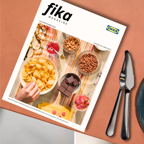 Front cover of IKEA's "Fika Magazine" featuring a top-down view of a table spread with snacks like potato chips, chocolate squares, nuts, and candies.