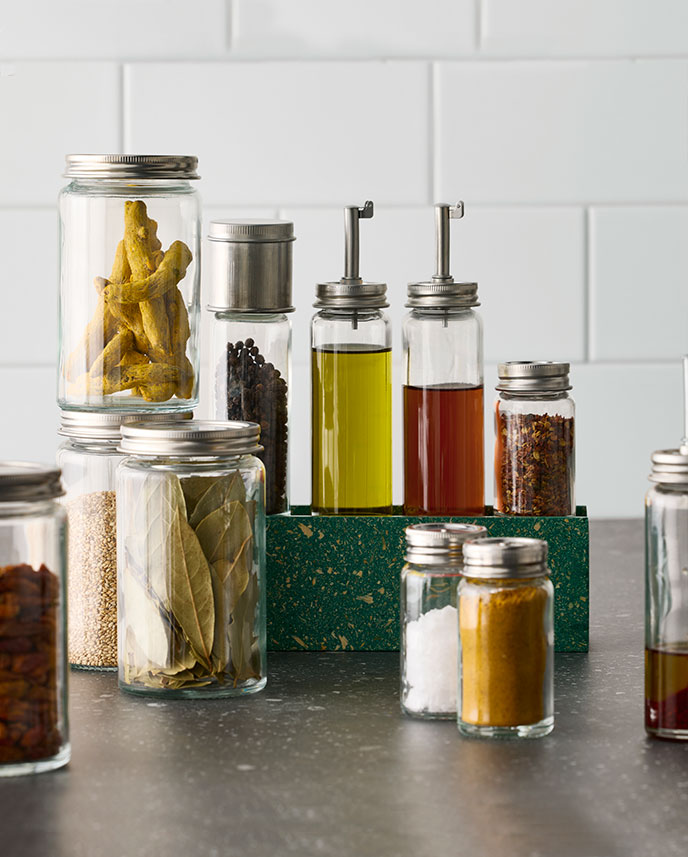 A countertop displays a range of spices in glass jars, including a CITRONHAJ oil/vinegar bottle.
