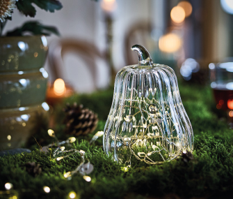 Decorative glass pear with lights on moss and natural accents.