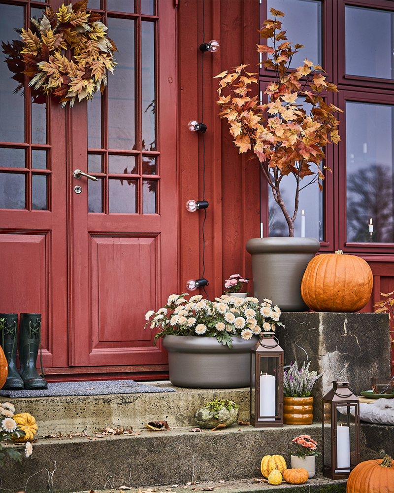 An autumn-themed outdoor staircase decorated with pumpkins and a door decorated with a HÖSTAGILLE artificial wreath.