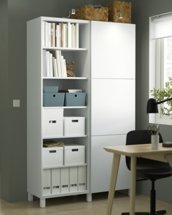 Armario y estantería alta en color blanco sobre una pared verde oscuro, organizada con libros, cajas y archivadores.