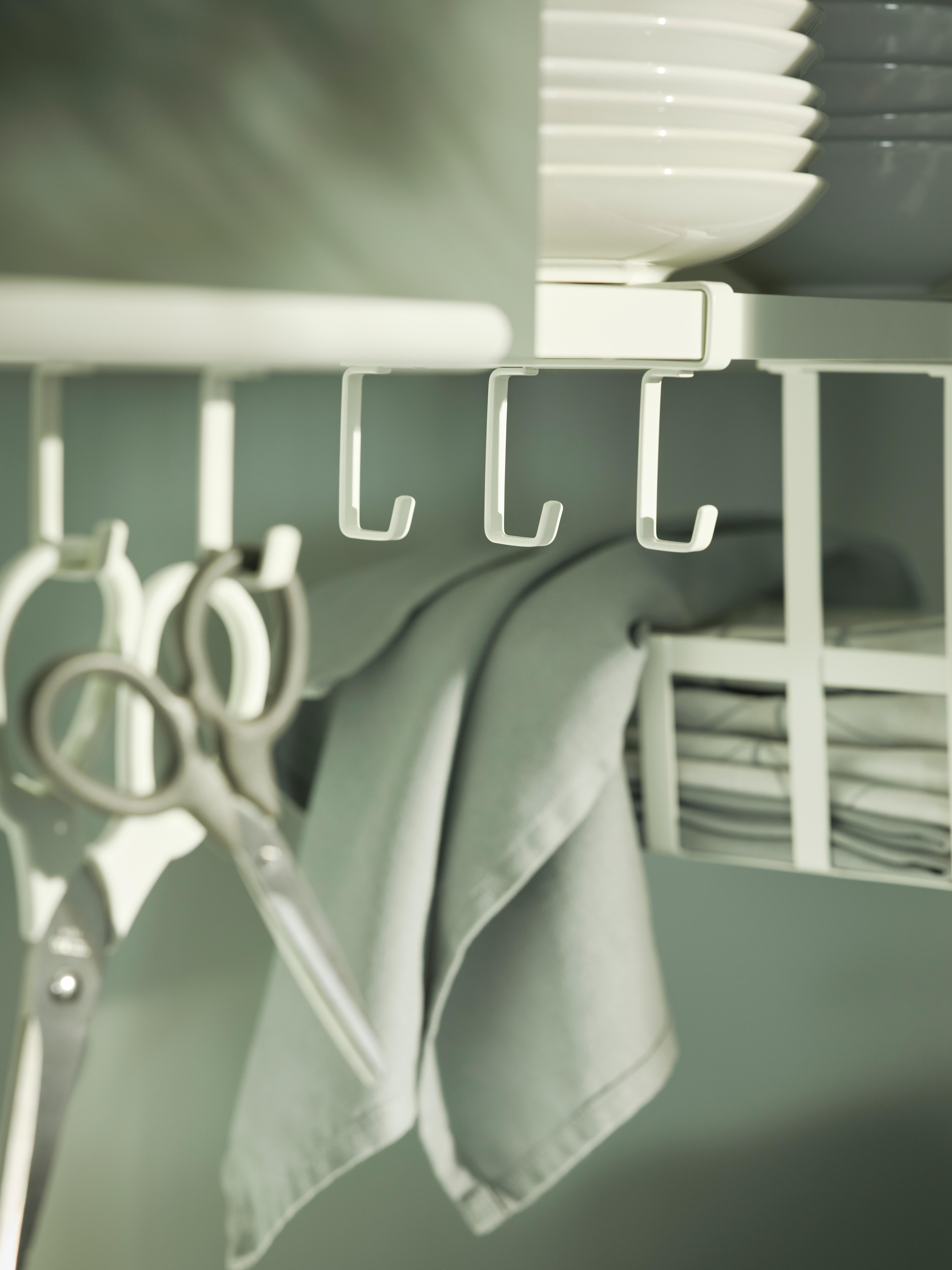 Organizador de cocina con ganchos, tijeras y paños doblados.
