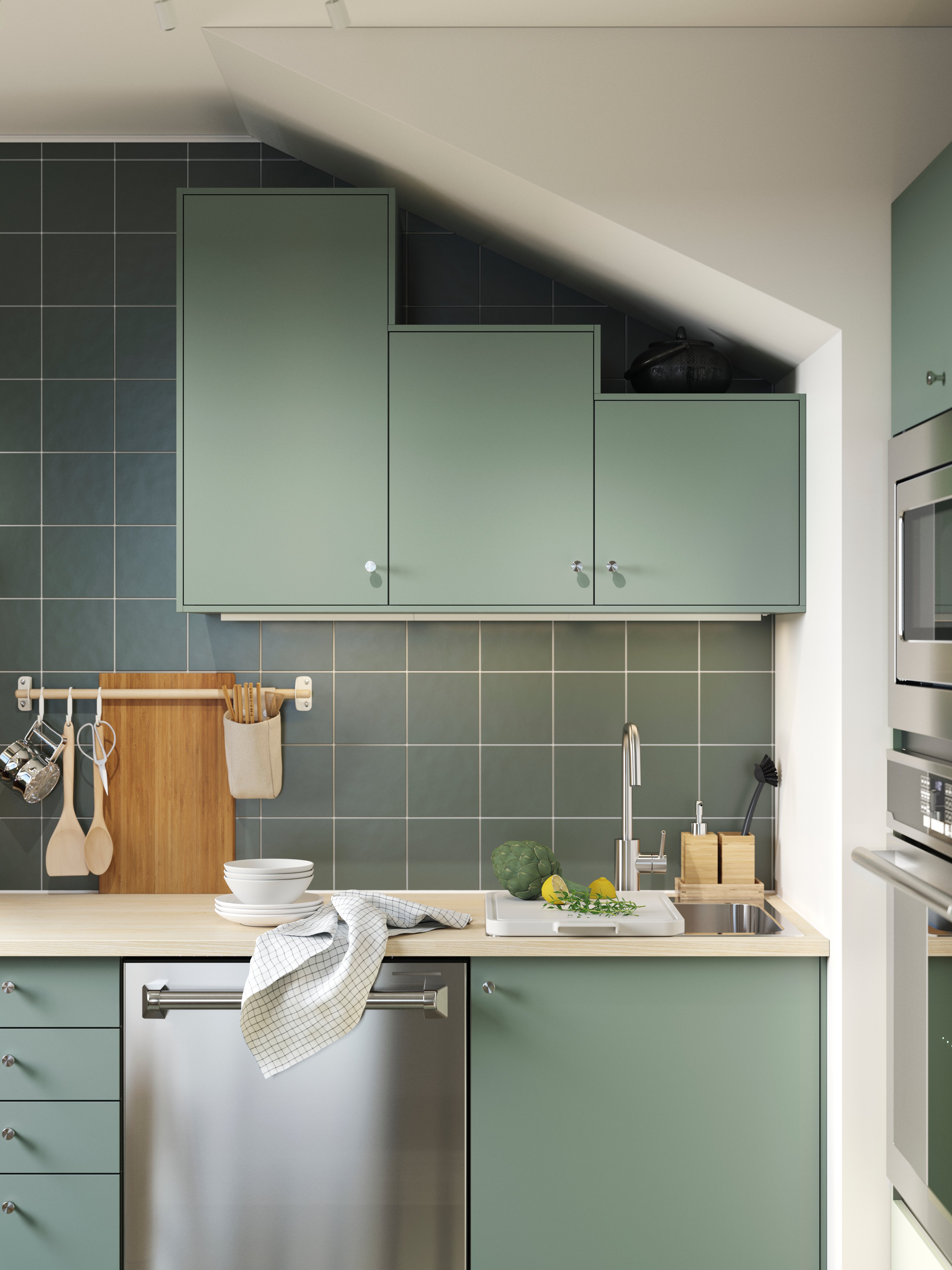 Cocina moderna con gabinetes verdes, fregadero y encimera de madera.