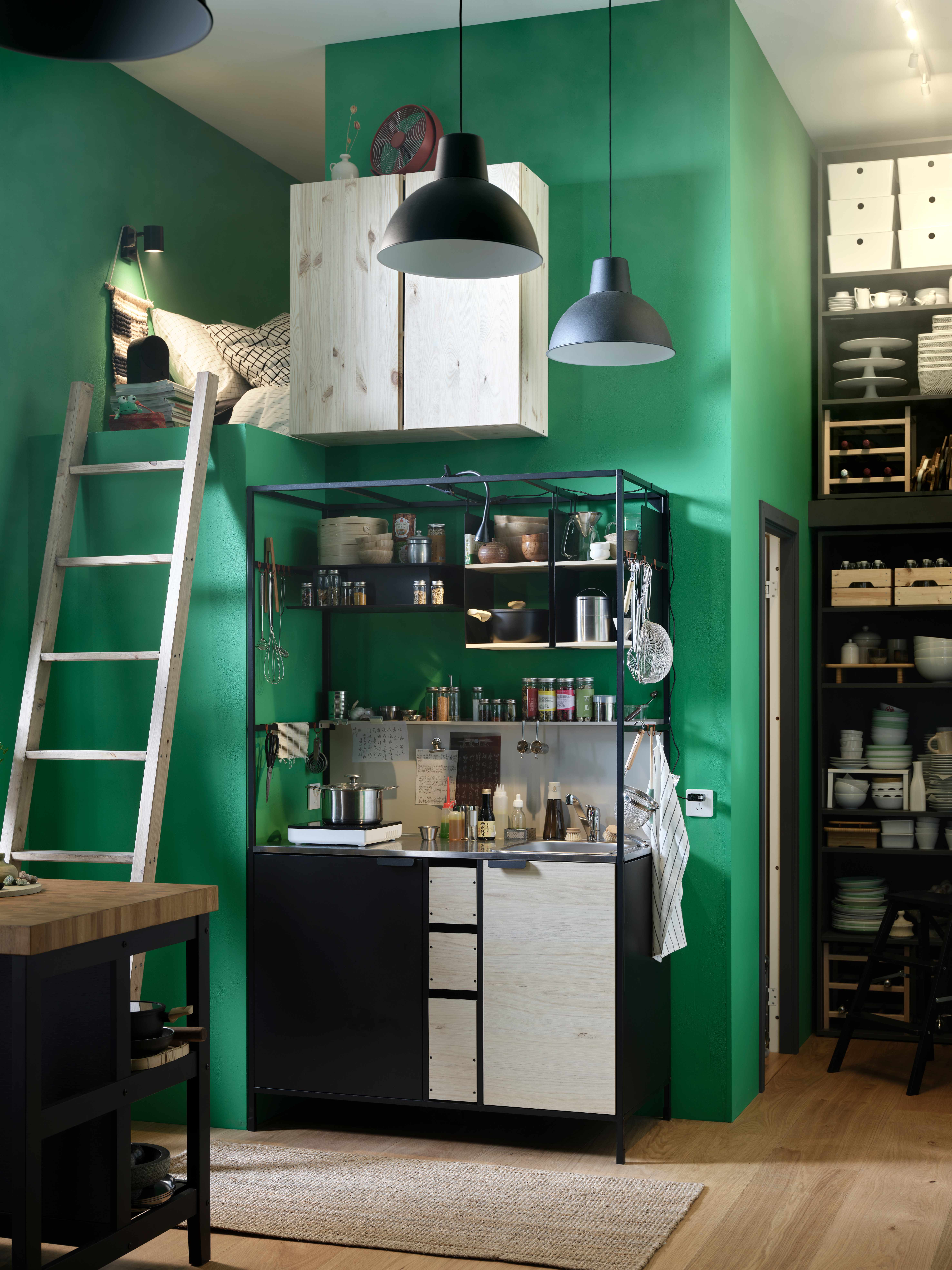 Compact loft-style kitchen with mezzanine, ladder, and green walls