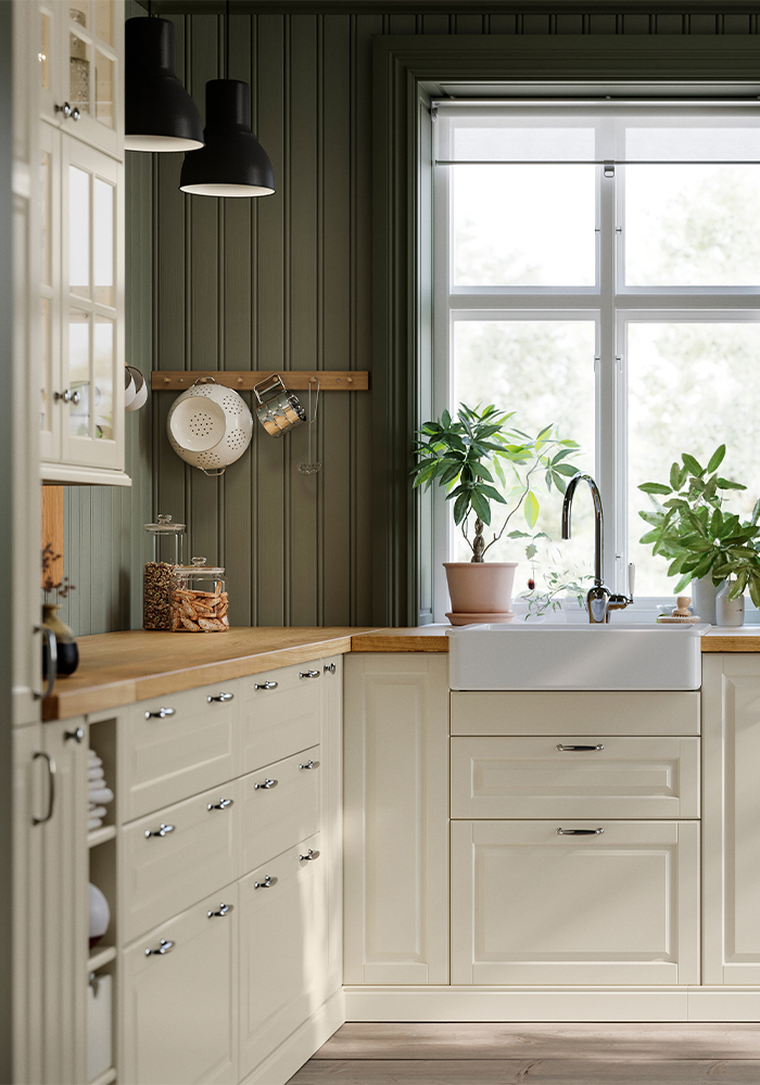 Bright kitchen with a sink beneath a window and decorative plants.