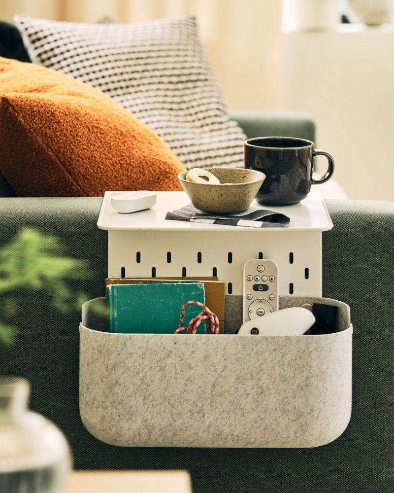 A softly sunlit space with a grey-green MALMKÖPING two seat sofa with coffee accessories on a KRAMPHULT armrest tray