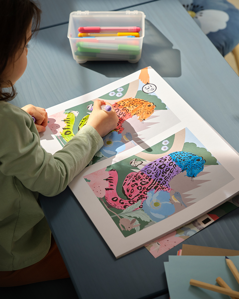 A child colours a leopard in the ALPTALL activity book which has colouring pages and games.