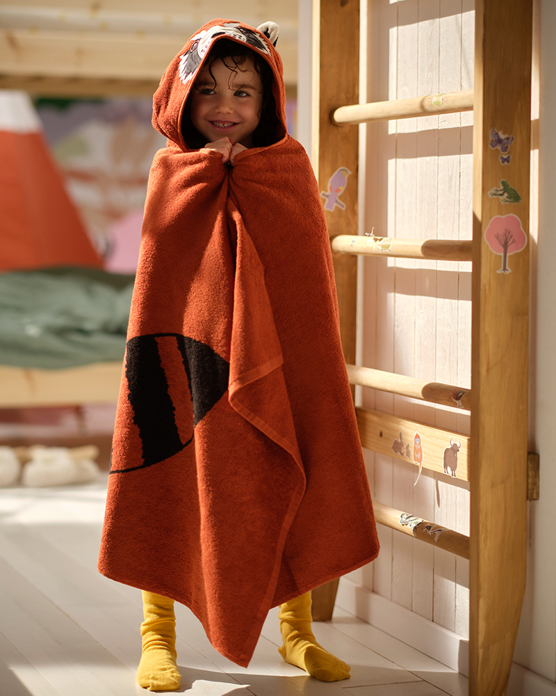 A child dries off with a cotton ALPTALL red panda towel with hood after a bath.