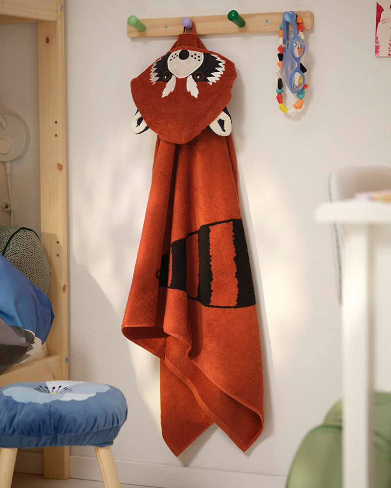 A cotton ALPTALL red panda towel with hood hangs on a hook in a child’s bedroom.
