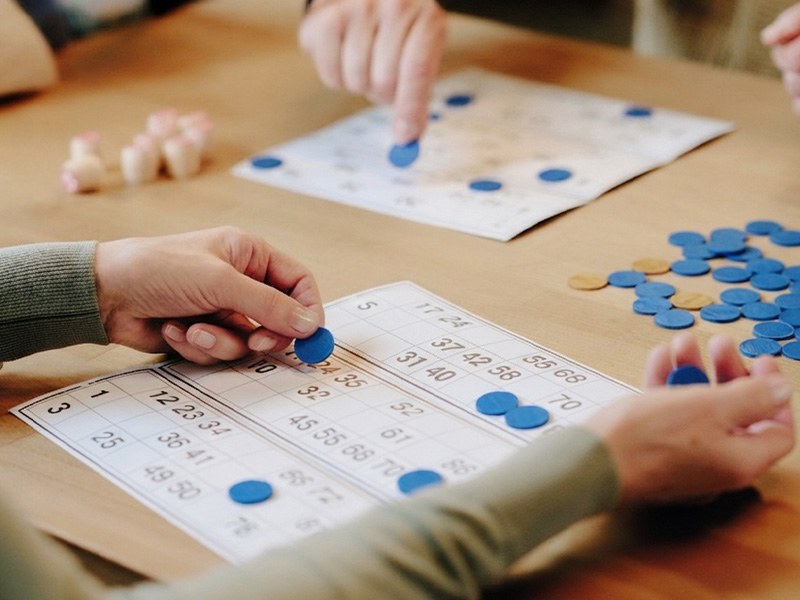 People playing bingo with blue markers on numbered cards.
