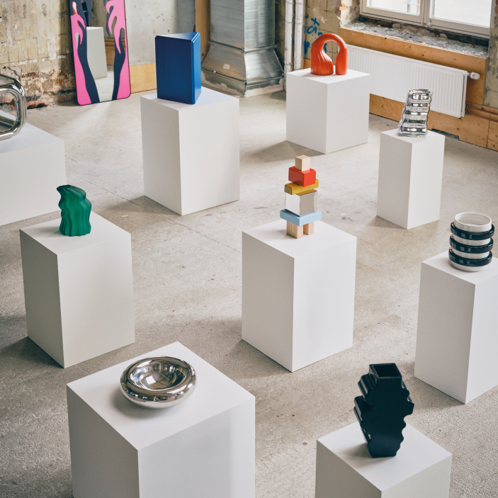 Design objects displayed on white pedestals.