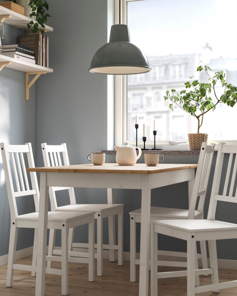 PINNTORP wooden dining table with four white matching chairs and a hanging pendant lamp in a bright dining room.