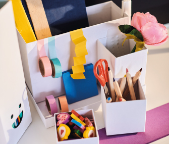 Organizador de escritorio blanco con lápices, tijeras, cintas adhesivas y accesorios escolares.