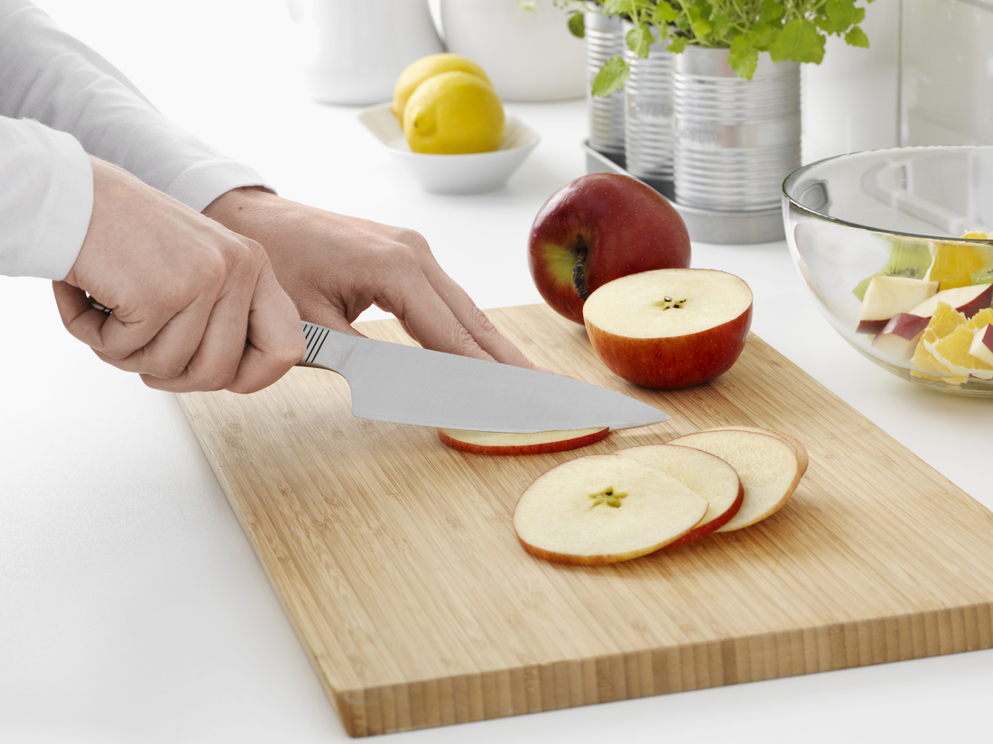 Una persona corta una manzana con un cuchillo en una tabla de madera.