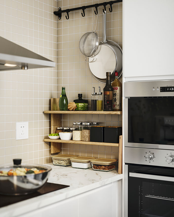 A narrow kitchen wall where two KLAVRESTRÖM oak wall shelves have been fitted above the worktop.