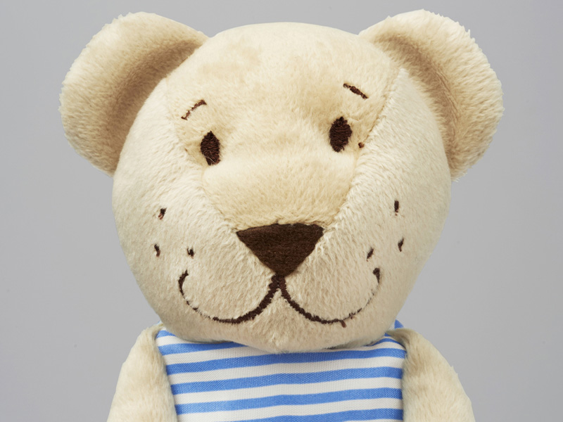 Teddy bear wearing a striped shirt with a red heart.
