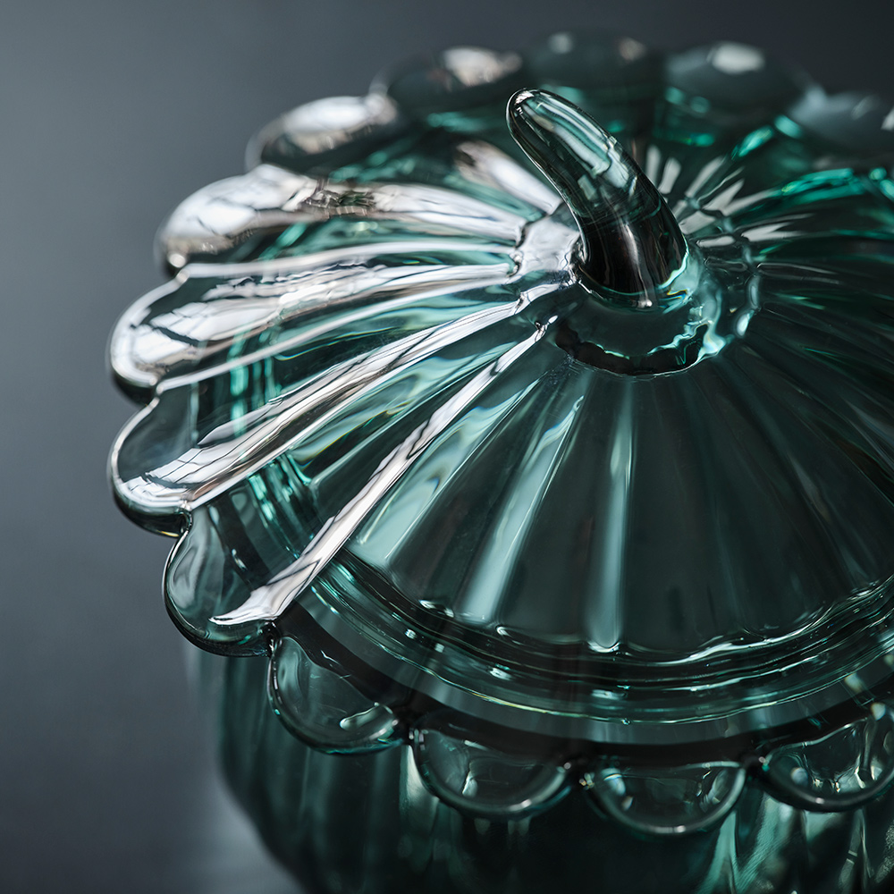 A close-up of the SNÖSISKA bowl with lid. The dark grey-green glass reflects the light in mesmerising way.