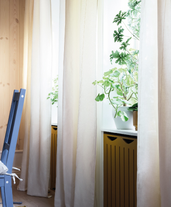 Cortinas claras junto a una ventana con plantas.