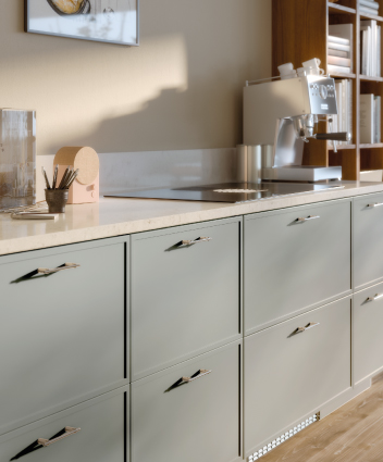 Mostrador de cocina con gabinetes gris claro, cafetera espresso y estantería de madera.