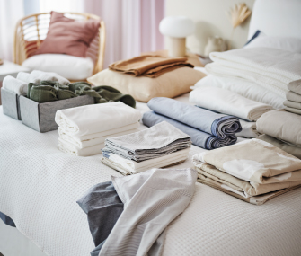 Ropa de cama y textiles doblados y organizados sobre una cama.
