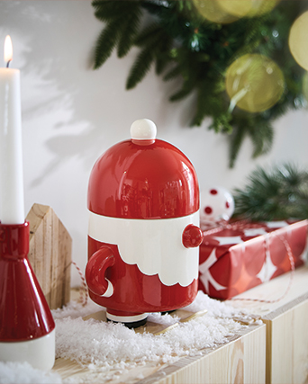 Adorno cerámico de Papá Noel sobre esquís junto a vela y regalo navideño.