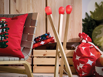 Lámparas decorativas con forma de cerillos de madera junto a un sillón y adornos navideños.