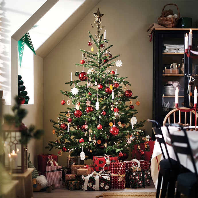 Árbol de Navidad decorado con esferas rojas y estrella dorada rodeado de regalos.