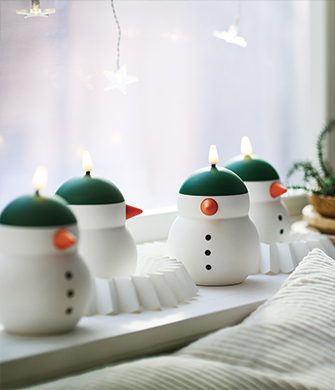 Velas LED decorativas con forma de muñecos de nieve alineadas en el repisa de la ventana.