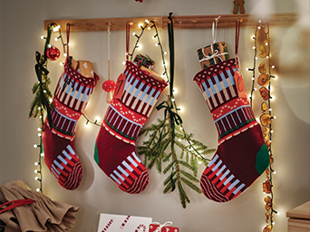 Christmas stockings hanging on a wooden rack decorated with string lights.