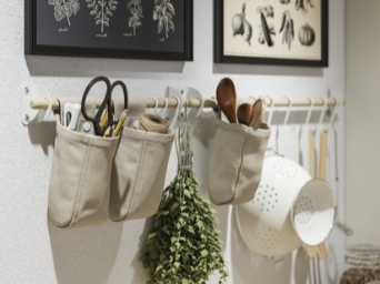 Utensilios de cocina y hierbas aromáticas colgadas en una pared de cocina bien organizada.