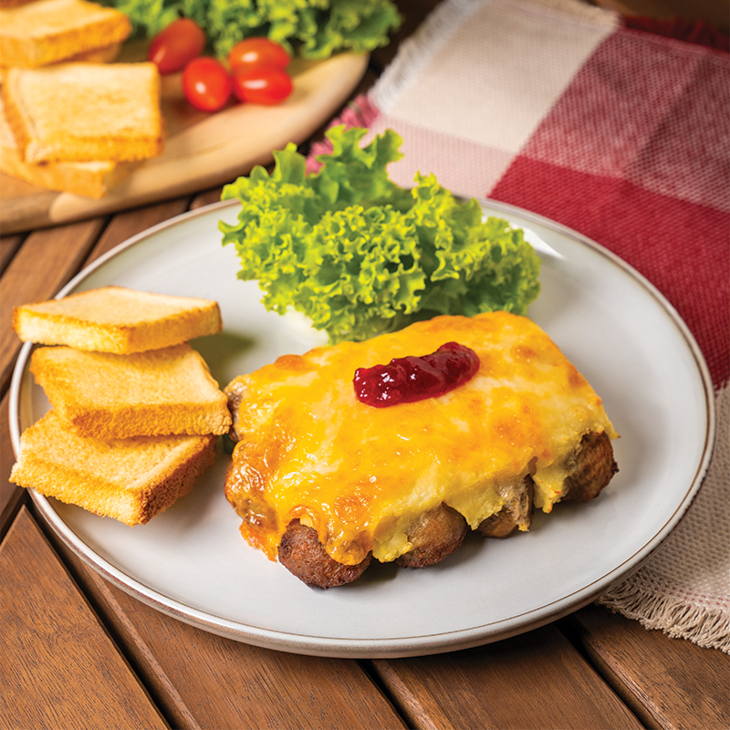 Plate of baked meatballs with melted cheese, jam, toast, and fresh lettuce.